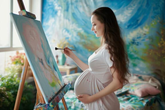 Femme enceinte pratiquant la peinture sur chevalet lors d'une séance d'art-thérapie en périnatalité